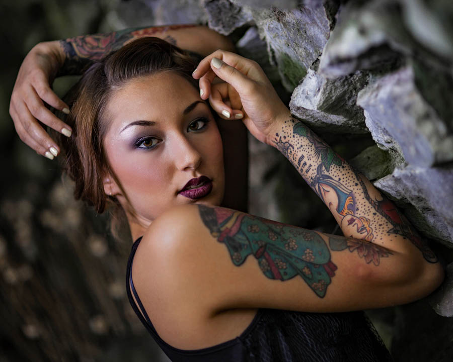 asian woman model with tattoos in a cave with rocks