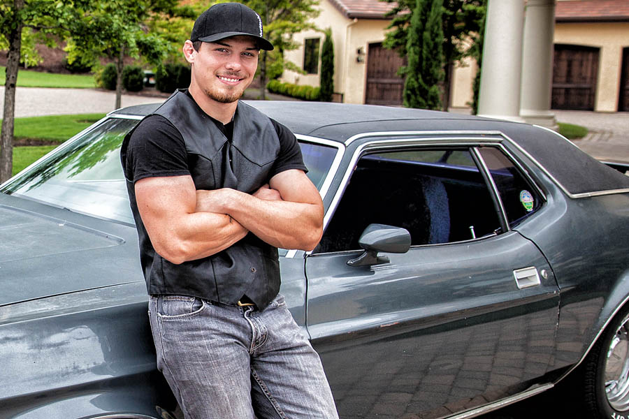 man standing with arms folded against mustang car