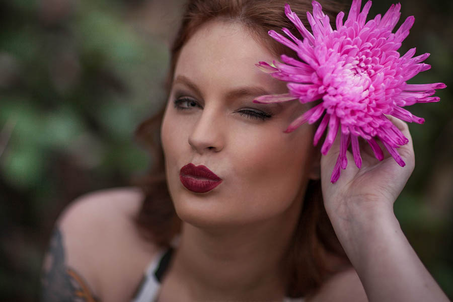 woman with light fair skin posing holding flower