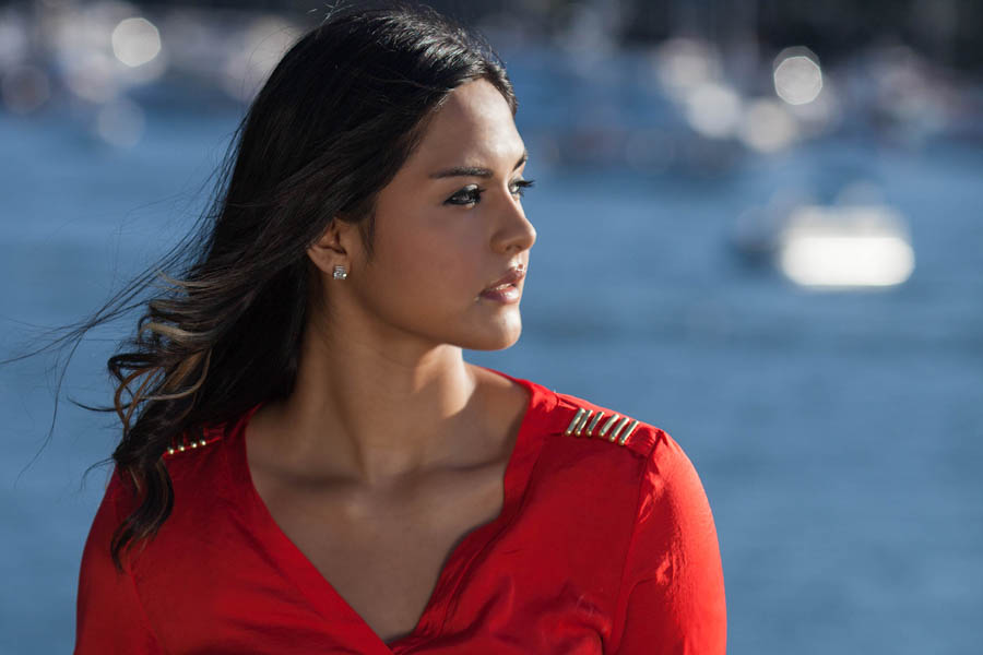 woman facing blue river and sun for side profile portrait