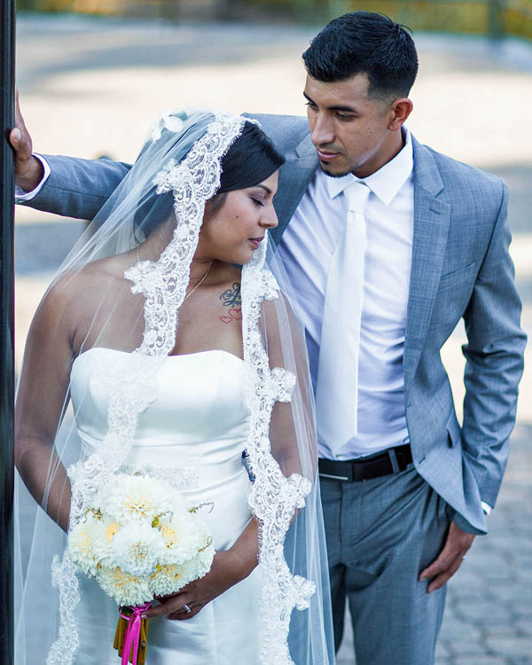 bride and groom with priest offering communion